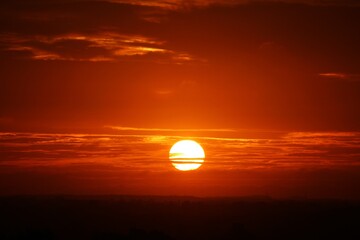 romantic sunrise with close-up of the bright sun with light veil clouds
