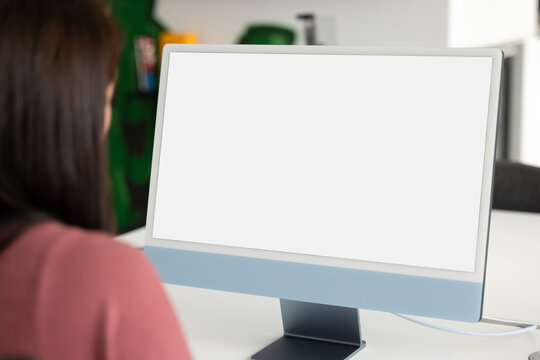 White blank screen of computer monitor on workplace table of female office employee. Business woman working at clean display with copy space, using Internet technology for job communication