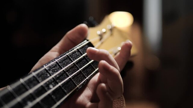 Child left hand playing ukulele. Close-up