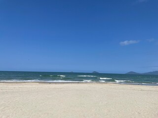 Tropical beach with palm trees. Umbrellas on the beach. Beautiful tropical beach with blue sky and white cloud background. Summer vacation and nature environment concept.