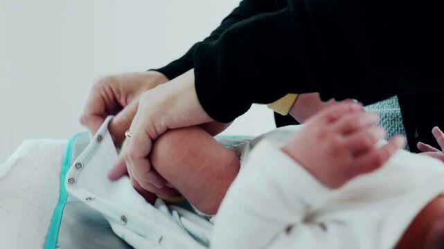 Gentle Dressing by Mother - Newborn's Legs in Clothes. A close-up of a mother dressing her newborn's legs, capturing the delicate and tender process in the early days of the infant's life