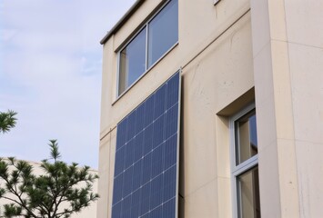 Obraz premium Modern building solar panel. Large solar panel mounted on beige building facade with contemporary windows showcasing sustainable architecture design.