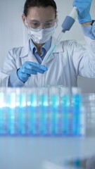 Woman scientist wearing lab coat, blue medical gloves, mask and protective glasses is using...