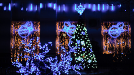 A street is lit up with Christmas lights and decorated with light trees and branches. Christmas and New Year illuminations. Festive background.
