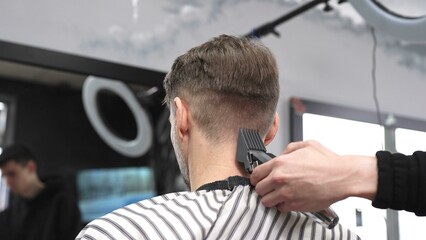 Professional hairstylist trimming client's hair using electric clippers, creating sleek, contemporary haircut with expert technique in modern barbershop setting