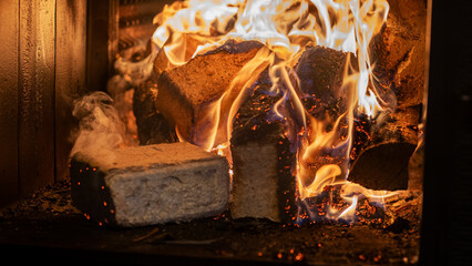 Eco-friendly compressed wood briquettes ignite a warm, inviting fire in a modern stove, showcasing...
