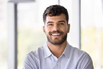 Head shot portrait young Arabic man dressed in casual blue shirt pose indoor. Profile picture of...