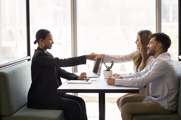 Couple and sales manager, bank advisor, real estate agent shaking hands start negotiate at formal meeting in office. Clients buying company services, handshaking consultant saleswoman express respect