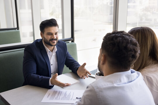 Sales manager and clients discussing term of agreement met in company office. Couple purchasing property, negotiating deal, ready to sign contract paper finalize formal meeting with professional agent