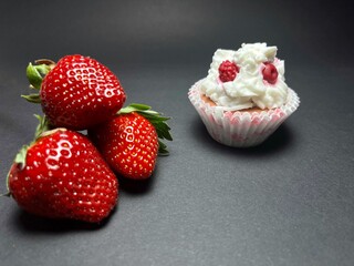Strawberry and chocolate cupcake with cream on black background
