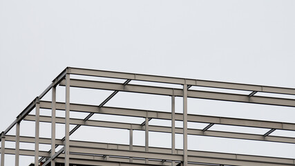 building frame made of metal beams during construction against grey sky