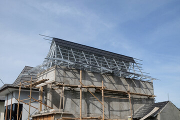 Fototapeta premium Residential house under construction with lightweight steel roof trusses under blue sky. Modern housing development and building industry concept