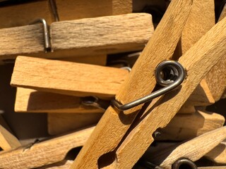 Clothespins beige wooden and plastic colorful clothespins lie in a pile under the sun rays taken from a close distance together with silver metal springs