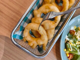 Homemade crispy onion rings with tomato sauce and salad