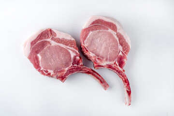 Raw dry aged trimmed bone-in pork loin chops cutlets offered as top view on white background