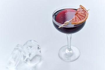 dark red cocktail in a low glass with a slice of lemon