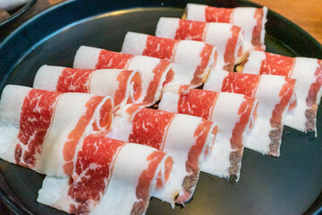 A beautifully arranged platter of hot pot meat slices showcases thinly sliced beef and pork,...