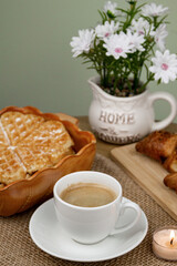 A cup of coffee, waffles and croissants on the table. Breakfast with coffee