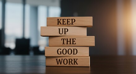 Wooden blocks stacked to form the phrase "KEEP UP THE GOOD WORK" on a dark table in a modern office setting. Represents motivation, encouragement, productivity, recognition, teamwork, dedication