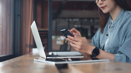 Asian student studying online, using mobile phone and laptop computer. Casual business woman, freelancer using smartphone searching the information during working on laptop at coffee shop, e-learning