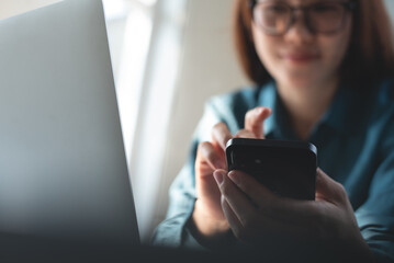 Business woman using mobile phone, surfing the internet during working on laptop computer at modern office. Casual business woman online working from home office, connecting wifi, online shopping