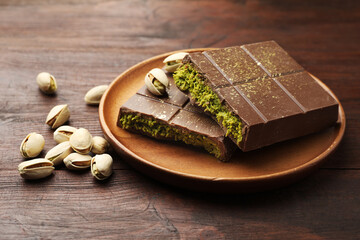 Pieces of tasty Dubai chocolate with pistachios and knafeh on wooden table, closeup