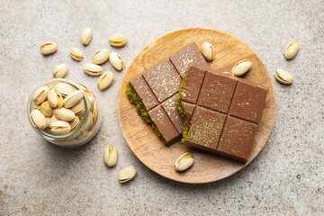 Pieces of Dubai chocolate bar with pistachios and knafeh on grey table, flat lay