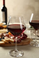 Red wine and different snacks served on light grey table, closeup