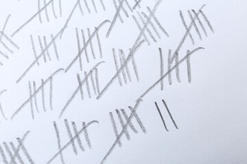 Counting days by drawing sticks with pencil on white background, closeup