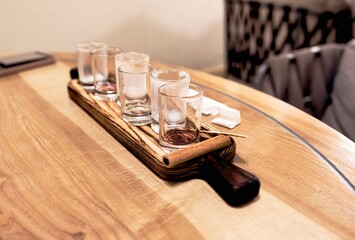 Empty glasses of drunken alcohol on a wooden server board in a cafe.
