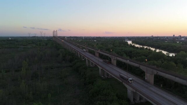 Truck traveling on Bartolome Mitre bridge transports wood at dusk, Argentina