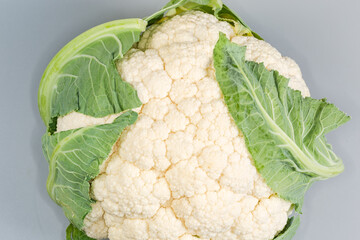 Whole raw cauliflower head, top view on a gray background