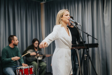 A band is performing live with a female singer, drummer, and keyboard player. The musicians are...
