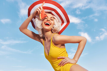 Cheerful woman in yellow swimsuit enjoying summer with watermelon on a sunny day