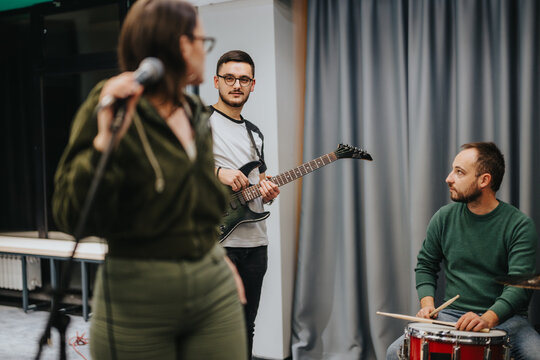 Three musicians collaborate during a band practice session, with each focusing on their respective instruments.