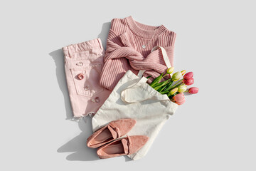 Fashion spring outfit. Pale pink jumper with bouquet of tulips flowers in bag,  jeans and loafers....