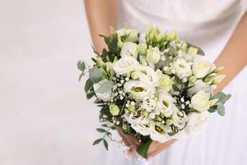 Bride with beautiful wedding bouquet on light background, closeup. Space for text