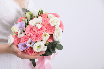 Bride with beautiful wedding bouquet on light background, closeup. Space for text