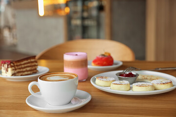 Delicious cottage cheese pancakes, desserts and aromatic coffee served on wooden table in cafe