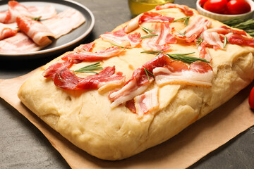 Delicious focaccia bread with bacon and rosemary on black table, closeup