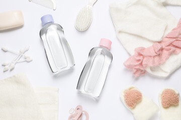 Baby oil, clothes and bath accessories on white background, flat lay