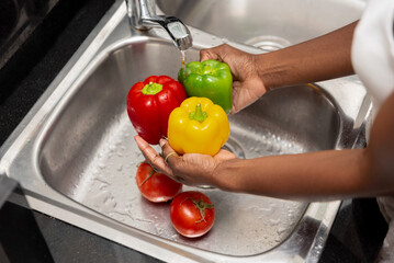 close up of Fresh colorful Bell Peppers and tomatoes Being Washed in Kitchen Sink
