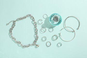 Stylish accessories and perfume on light blue background, flat lay