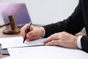 Notary signing document at table in office, closeup