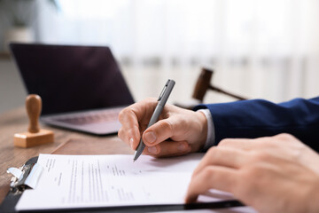 Notary signing document at table in office, closeup