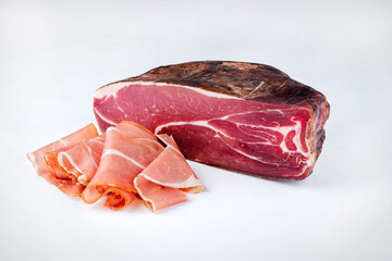 Traditional artisan and handcrafted air-dried Prosciutto offered as close-up on with background -...