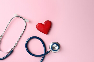 Cardiology. Stethoscope and red decorative heart on pale pink background, flat lay. Space for text