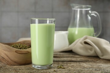 Fresh mung bean juice in glass and seeds on wooden table, closeup
