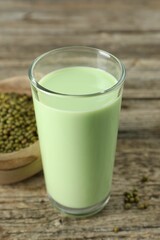 Fresh mung bean juice in glass and seeds on wooden table, closeup