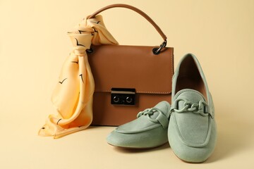 Leather bag with handkerchief and loafers on beige background, closeup